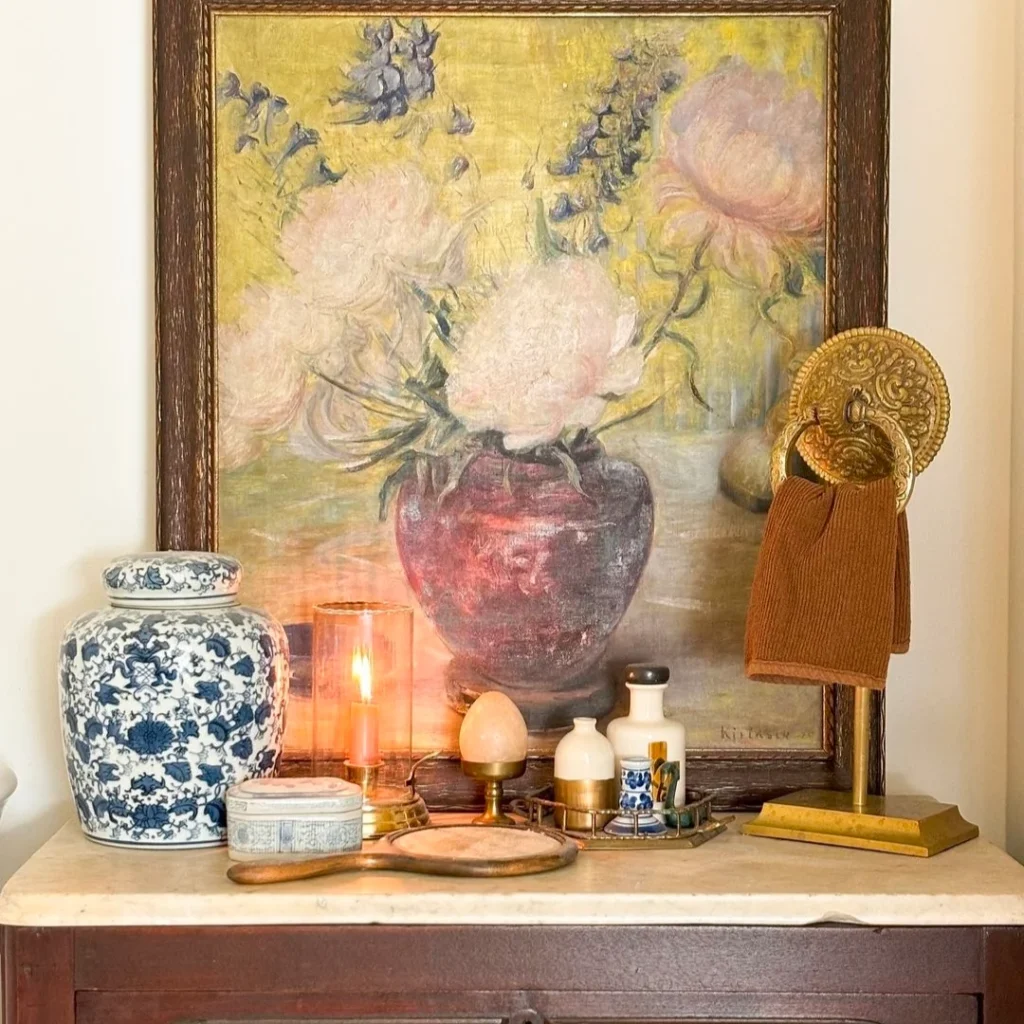 A hand painted big size wall painting is placed on the console having vintage essentials to granny chic living room.