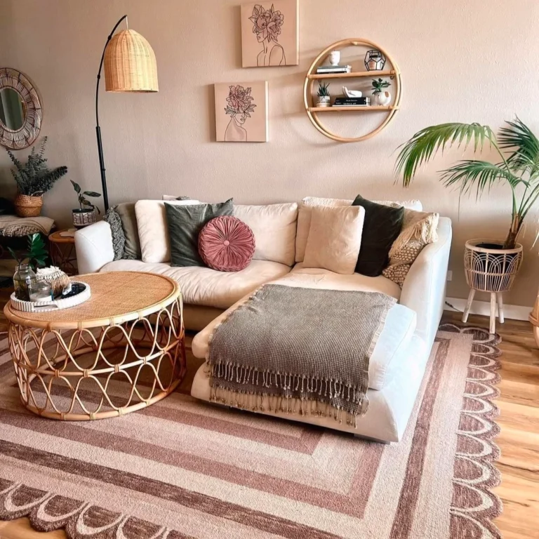 A white and brown-themed boho chic living room ideas, is decorated with a canned round table, side lamp, plant pot, L-shaped small slow-slung white sofa, and two wall hangings in a beige tone in the background.