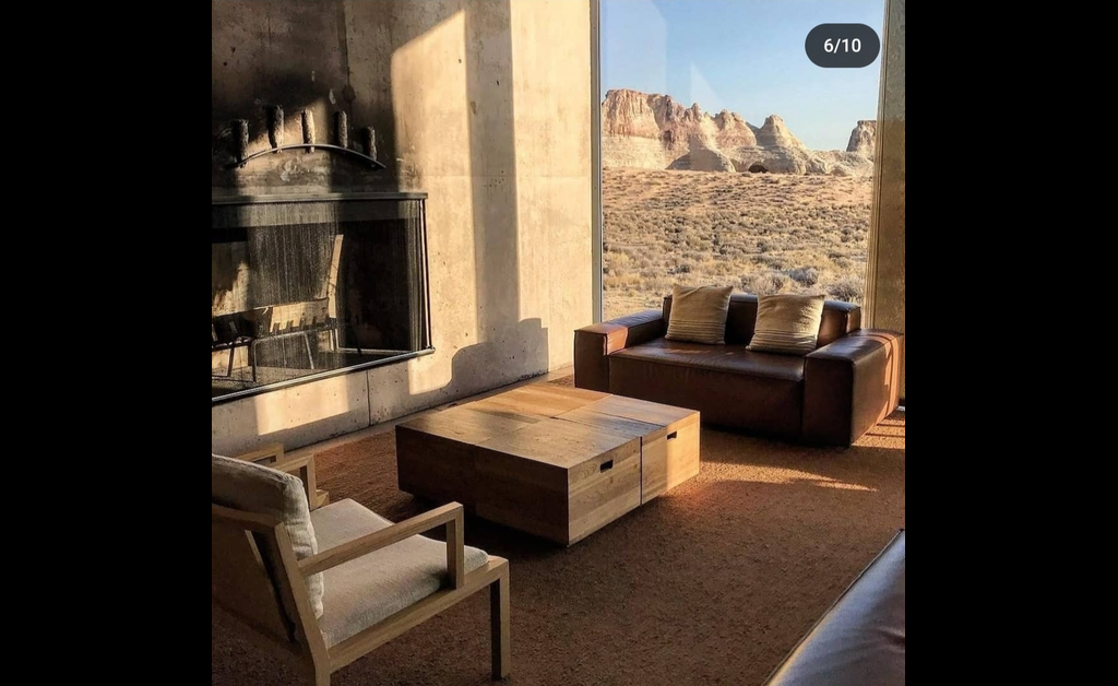 a low slung dark brown leather sofa plaed in front a lrge glass window, facing desert outside.