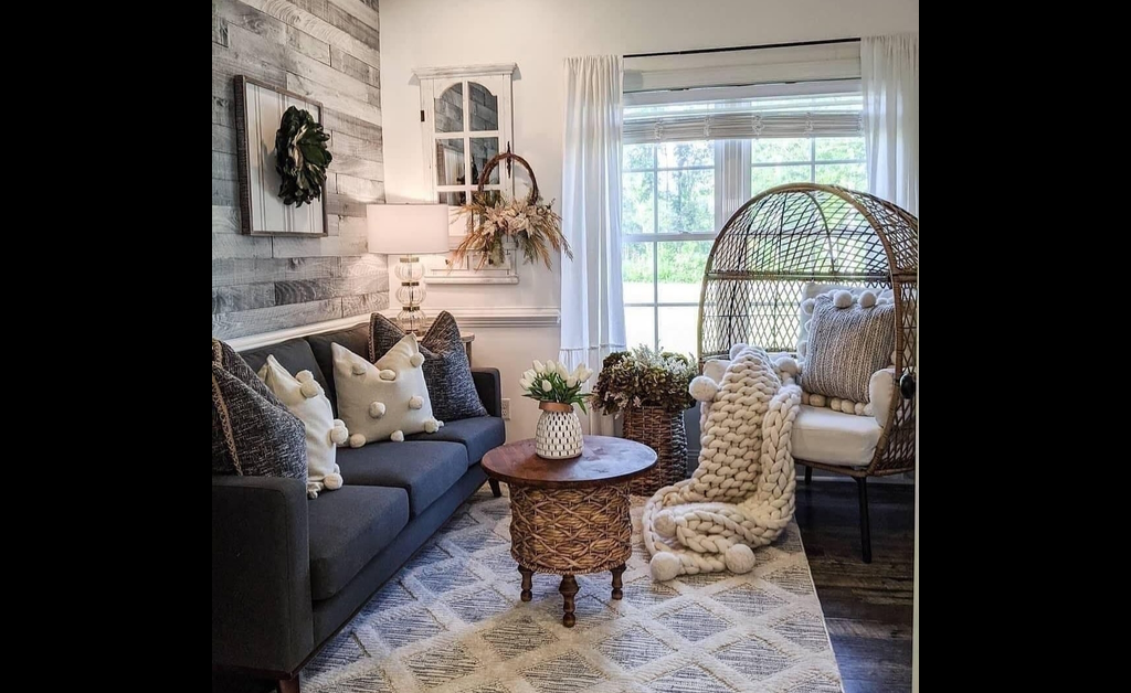 A raised rug on floor, woven wool throws in egg hanging chair and grey sofas with fluffy cushions.