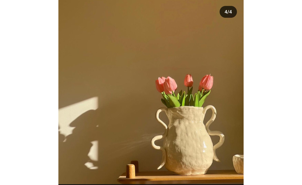 a Japanese traditional ceramic vase with pink flowers in it placed on wooden console.