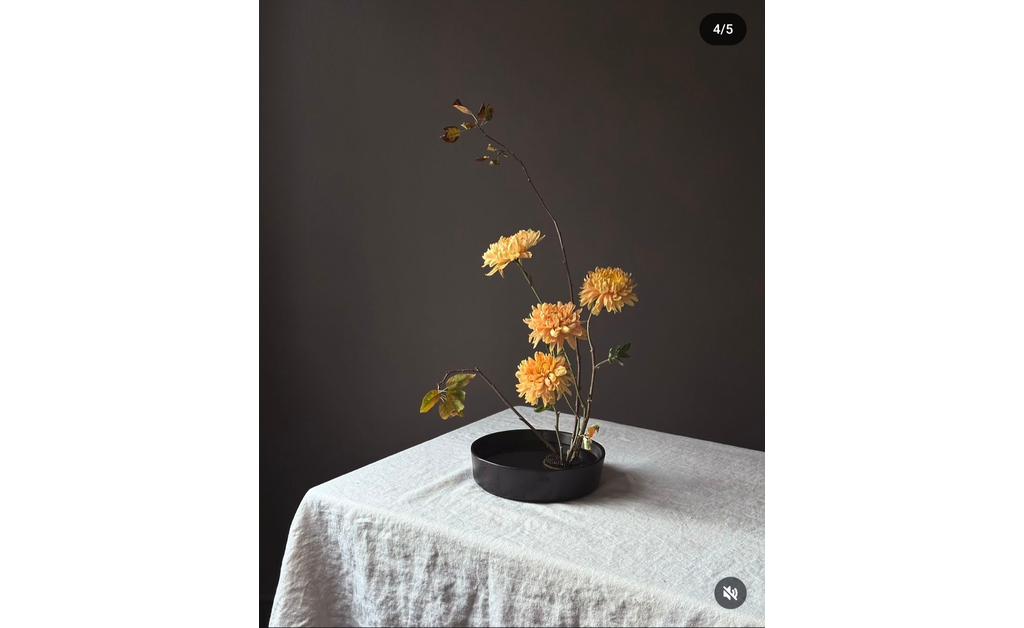 Japanese-style ikebana in ablack bowl placed on a table.