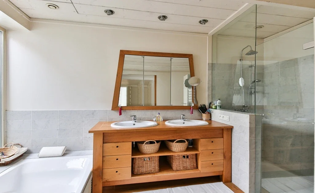 a rectangular wodden frame mirrore on above the sink. there are storage baskets too.