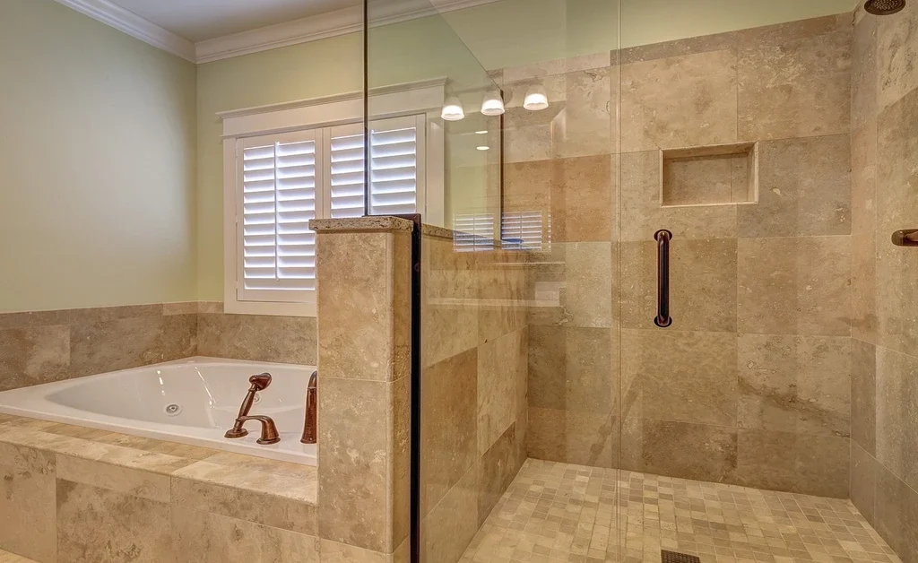 A monochrome japandi bathroom. glass door is differentiating between tub and shower area.