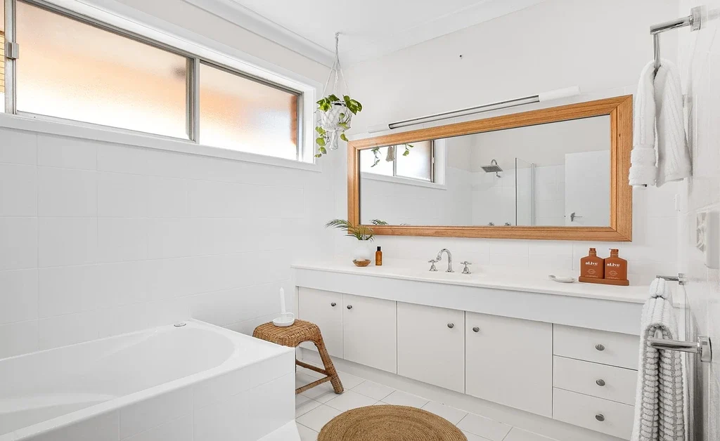 A large rectuangular mirror placed on wall. wall mounted towel handles are also there.