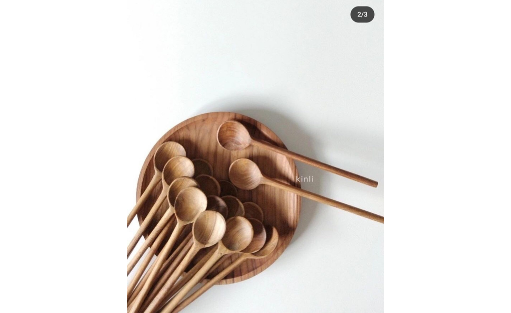 A wooden bowl having lots of wooden spoons in it.