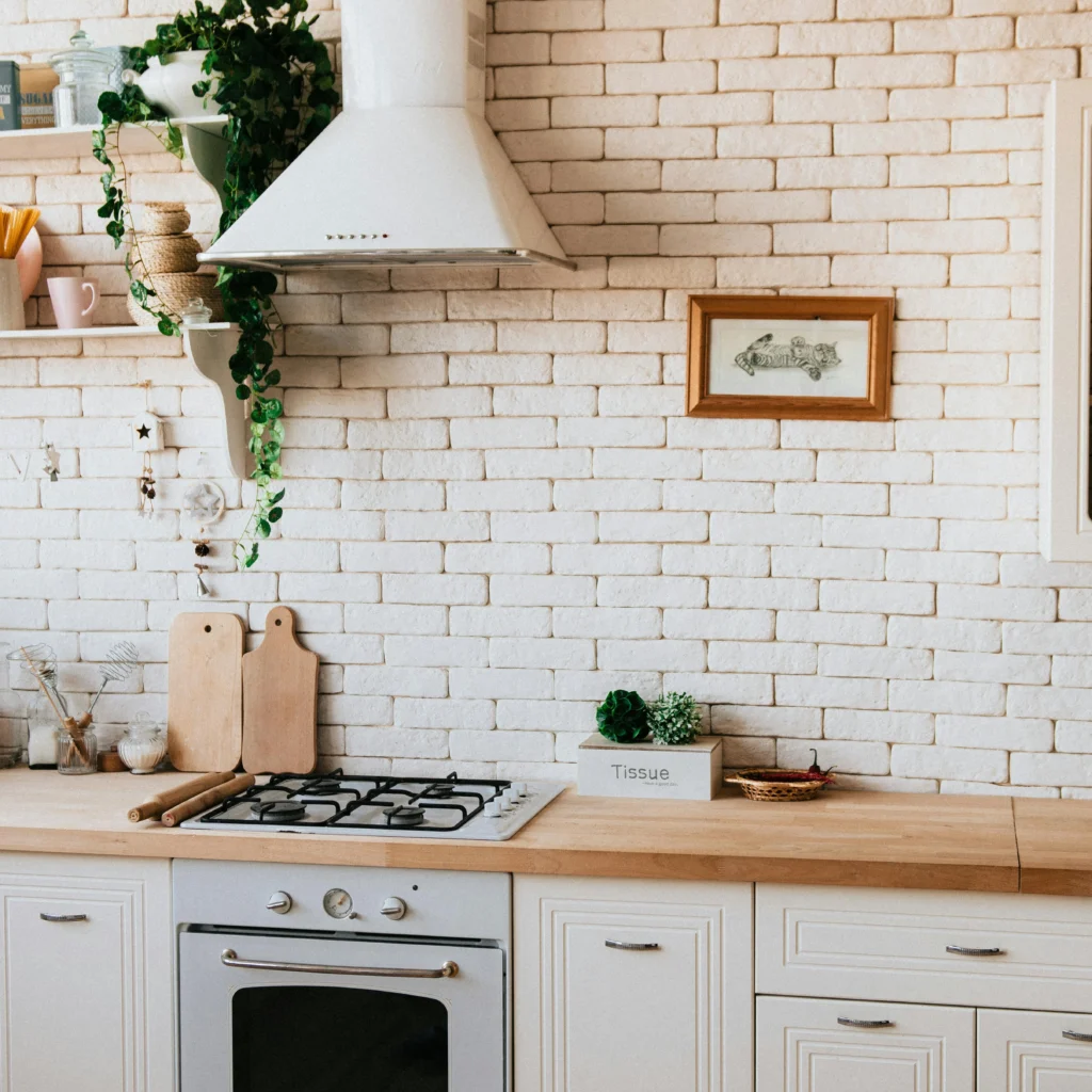 artifical leaves hanging fro from the above cabinets in white kitchen.