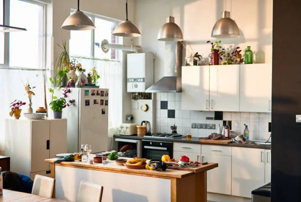 pendants lights are hanging from the roof  top. dried leaves in decorative glass bottles  placed above the kitchen cabinets.