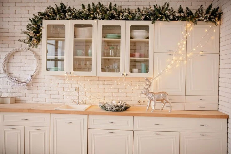 festive leavse are placed above the cabins. the glass door is showing plates in the cabinets. wreath and lights can also be seen.